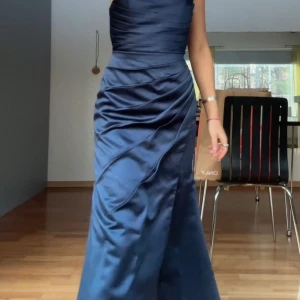 Mörk marinblå långklänning från JJ's House - Köpt 2024 och den är i minsta storlek från hemsidans mått men sytt upp den hos skräddare enligt mina mått ( skriv privat för måtten). Elegant mörk marinblå långklänning i satin med v-ringning och spaghetti-band. Klänningen har en stilren siluett med rynkat liv och hög slits. Perfekt för speciella tillfällen såsom bröllop för anhöriga eller bal.