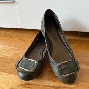 Marco Tozzi Ballerinaskor khaki Stl 37 - *Eleganta ballerinaskor från Marco Tozzi i en fin khaki nyans.  *Skorna har en dekorativ detalj framtill och ett mönster av små hål som ger en luftig känsla.  *Perfekt för både vardag och fest.  *Mycket bekväma.  *Äkta skinn.  *Använda vid 2 tillfällen.  *Djurfritt och rökfritt hem.