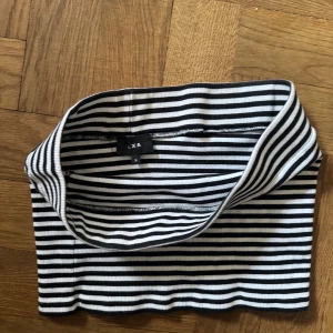 Randig tubtopp från LXA - Snygg och stilren tubtopp från LXA Linn Ahlborgs märke med klassiskt svartvitt randigt mönster. Så snygg att ha själv eller under kavaj! Använd men i fint skick!!