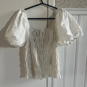 Vit blus från Pieces - Säljer en söt vit blus från Pieces med puffiga kortärmar och smockdetaljer. Storlek M men passar som S också!💘💘