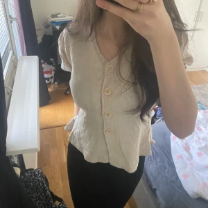 Beige kortärmad blus med knappar - Säljer en stilren beige blus med korta ärmar och stora knappar framtill. Perfekt för en avslappnad men ändå chic look. Passar bra till både jeans och kjol. (Pris går alltid att diskutera 💕)