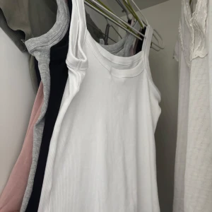 Vita ribbade linnetoppar från Gina Tricot - Säljer tre  ribbade linnetoppar från Gina Tricot. Perfekta för sommaren med en stilren design och bekväm passform. Passar till många olika outfits och tillfällen. Grå, vit och svart