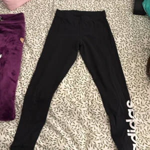  leggings från Adidas - Snygga svarta leggings från Adidas med vit logga på benet. Perfekta för träning eller en avslappnad dag. Tillverkade i ett stretchigt material för bästa komfort.