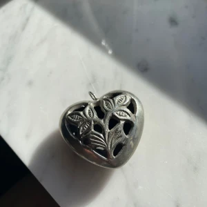 Hjärtformad silvrig berlock - Jag säljer en unik berlock med blommönster på. Den är tidlös och passar till allt🩶