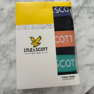 3-pack kalsonger från Lyle & Scott - Säljer ett 3-pack kalsonger från Lyle & Scott i storlek XXL. Färgerna är svart, orange och grön med bred resår och logotypen tryckt runt midjan. Tillverkade i bomull med stretch för extra komfort. Köpte fel storlek därav jag säljer dom