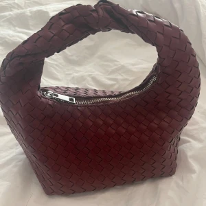 Vinröd flätad handväska från Gina Tricot - Säljer denna vinröda flätade handväskan från Ginatricot. Den är som nytt i skick och rymmer jättemycket och finns även en liten ficka inuti. Köpt för 400kr 💕