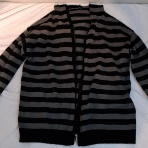 Svart och grå stickad hoodie - Säljer en svart och grå randig, stickad hoodie med dragkedja. Storlek står inte men skulle gissa M eller något sånt. 