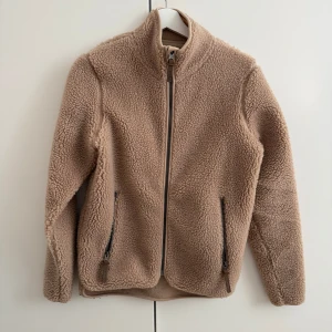 Beige teddyjacka från Strova - Mysig beige teddyjacka från Strova i storlek 32/34. Jackan har dragkedja framtill, två fickor med dragkedja och hög krage. Endast använd ett fåtal gånger. 💛