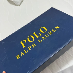Beige sneakers från Polo Ralph Lauren - Säljer ett par snygga beige sneakers från Polo Ralph Lauren med bruna detaljer och vita sulor. Skorna har snörning och en klassisk, låg profil som passar till många olika outfits.