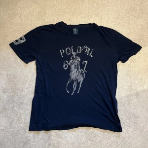 Mörkblå t-shirt från Polo Ralph Lauren - Tja, säljer denna snygga t shirt från Ralph Lauren. Den är lite urtvättad och sliten, därav priset!! Vid minsta fråga eller fundering hör av er🤝