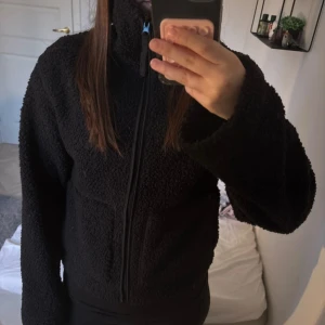 Svart teddyjacka - Mysig svart teddyjacka med hög krage och dragkedja framtill. Jackan har lång ärm och är tillverkad i ett mjukt teddy-material som passar perfekt för kyligare dagar💕