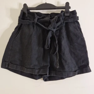 Shorts - Svarta shorts med gylf, knäppning och knytning runt midjan. Mid/high waist, Välanvända. Har bundlerabatt och låga priser så kolla gärna resten av mina annonser!!