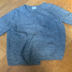 Grå kofta från H&M - Mysig grå kofta från H&M med rund halsringning och knappar framtill. Tillverkad i ett mjukt stickat material, perfekt för lager-på-lager. Klassisk och enkel design som passar till det mesta. Passar även folk med S eftersom den inte är så stor i storleken.