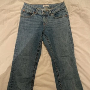 Blå jeansbyxor flared - Klassiska blå flared jeansbyxor med normal passform. Byxorna har fem fickor, knappgylf och bälteshällor. Perfekta till vardags och enkla att matcha med olika toppar.