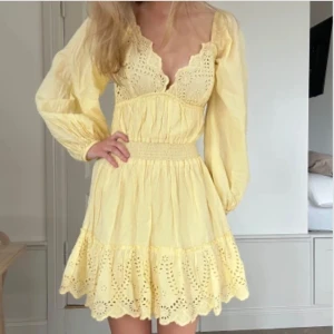 Gul kortklänning💓 - Söt gul kortklänning med långärmade puffärmar, djup v-ringning och broderade spetsdetaljer. Klänningen har markerad midja och volangkant nertill. Perfekt för vår och sommar!😊