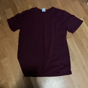 Vinröd t-shirt från Time to Lounge - Säljer en enkel vinröd t-shirt från Time to Lounge i storlek M. T-shirten har rund halsringning och korta ärmar. Perfekt för en avslappnad stil och passar till det mesta. Materialet känns mjukt och bekvämt.