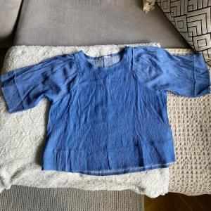 Blå blus med vida ärmar - Säljer en supersöt blå blus med rund hals och vida ärmar. Blusen har en lätt rynkad struktur i tyget. Perfekt för vår och sommar! Kommer tyvärr inte till användning längre därav säljer jag den. 