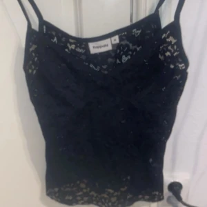 Svart spetslinne från Kappahl - Säljer ett svart linne från Kappahl med tunna axelband och vacker spetsdetalj över hela toppen. Perfekt att styla till olika outfits för en trendig look.