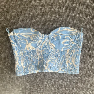 Blå och beige mönstrad bustier-topp - Säljer en blå och beige bustier-topp från Zara med mönster. Köpt på Plick och hon hade aldrig använt den o inte jag heller, när jag köpte den så va bygeln lite trasig men lätt att sy ihop!