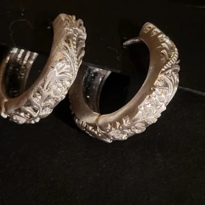 Silverfärgade vintage style  örhängen från Pilgrim - Säljer ett par snygga silverfärgade örhängen från Pilgrim med detaljerat mönster och bred båge. Tillverkade av minst 75% återvunnet material. Perfekta för att lyfta din stil.