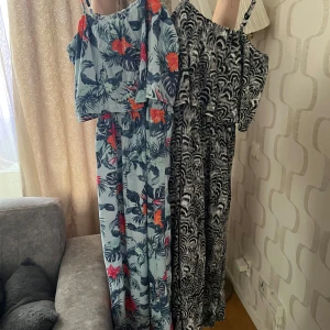 långklänning med blommigt mönster - Säljer tre somrig långklänning med gröna blad och stora röda blommor. Klänningen har smala axelband och en luftig passform, perfekt för varma dagar.