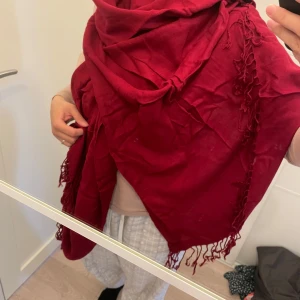 Mörkröd halsduk med fransar - Säljer en stor och mjuk mörkröd halsduk med fransar i kanterna. Perfekt att svepa runt halsen för extra värme och stil. Passar bra till både jacka och kappa.