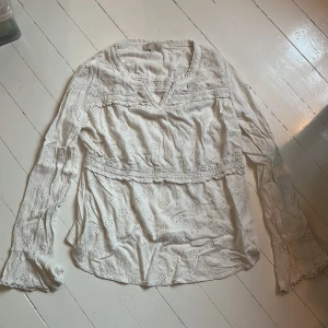 Vit blus med blommig brodering - Vit blus med blommig brodering. Har en v-ringning och trumpetformade ärmar. Har två volanger som går runtom blusen. Väldigt fin till ett par jeans eller kjol till sommaren. Skriv för fler bilder💞