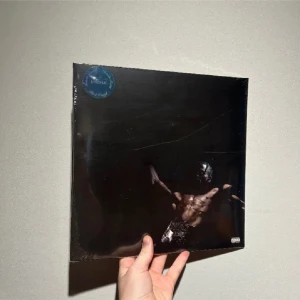 Utopia - Utopia är ett album av Travis Scott, med ett mörkt och stilrent omslag som passar perfekt för dig som älskar modern musik och coola samlarobjekt. Perfekt för unga vuxna som vill ha något unikt i sin samling.