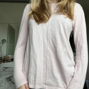 Alice bizous // Ljusrosa finstickad tröja // XS/34 - Supersöt ljusrosa stickad tröja med lång ärm och rund hals. Tröjan har en clean look med en diskret söm som går längs mitten både fram och bak. Perfekt att matcha med jeans för en chill stil.