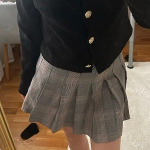 Grå rutig plisserad kortkjol - Säljer en grå plisserad kortkjol med klassiskt rutigt mönster. Kjolen har en snygg och ungdomlig vibe med tydliga veck som ger extra volym och stil. I storlek 34❤️använd fåtal gånger ifrån HM❤️Perfekt till hösten 