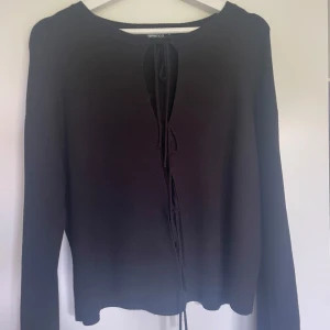 Svart kofta med snörning från Gina Tricot - Snygg svart kofta från Gina Tricot med lång ärm och cool snörning framtill. Perfekt för lager-på-lager och att styla med dina favoritjeans. Mjuk och skön, passar dig som gillar en enkel men trendig look.