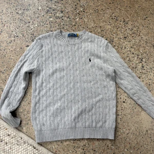 Grå kabelstickad tröja Polo Ralph Lauren - Kabelstickad grå tröja från Polo Ralph Lauren. Använd ett fåtal gånger. Pris: 800kr