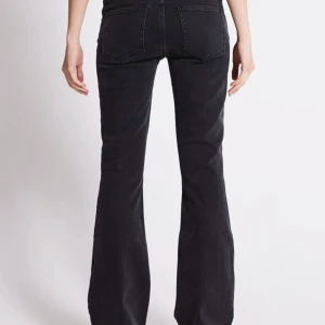 Svarta bootcut jeans med hög midja - Snygga svarta jeans med bootcut passform och relativt låg midja. Jeansen har klassisk femficksdesign och är tillverkade i ett mjukt denimtyg som sitter skönt. Perfekta till sneakers eller boots för en cool vardagslook.