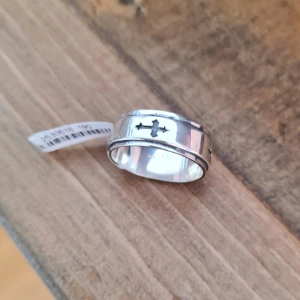 Silverring med kors guldfynd  - Stilren sterling silverring med ett utskuret kors på framsidan. Ringen har en bred, slät design med diskreta kanter som ger en cool och modern känsla. Perfekt för dig som gillar enkla men ändå uttrycksfulla smycken. Ringen är aldrig använd men inte putsad för att inte förstöra etiketten. Strlk 18 3/4
