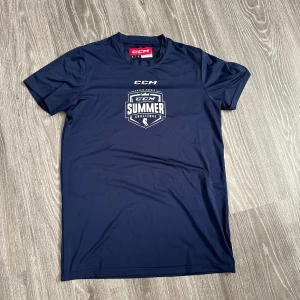 Mörkblå CCM Summer Challenge t-shirt - Sportig mörkblå t-shirt från CCM med tryck 'Summer Challenge' på bröstet. Klassisk rund hals och korta ärmar. Materialet är mjukt och lätt polyester, perfekt för aktiva dagar eller häng med kompisar. Snygg logga både fram och i nacken.