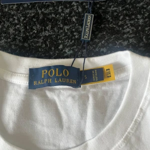 Vit t-shirt från Polo Ralph Lauren - Fräsch vit t-shirt från Polo Ralph Lauren i storlek S finns storlek M också. Klassisk rund hals och korta ärmar, med den ikoniska broderade loggan på bröstet. Tillverkad i mjuk bomull som känns skön mot huden. Perfekt för dig som gillar stilrena och tidlösa plagg.