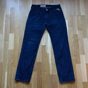 Replay MV 941A,034 Mörkblå Jeans - Replay jeans i modellen MV 941A,034 och färgen mörkblå. Storlek: 30 W, 34 L , Midja: 37.5 cm Ytterben: 96.5 cm Benöppning: 18 cm Material: 100% Cotton.