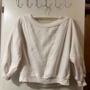 Vit sweatshirt med bred krage - Enkel och stilren vit sweatshirt med bred ribbad krage och muddar vid ärmslut och nederkant. Tröjan är off shoulder och har en loose passform och är tillverkad i mjuk bomull, perfekt för en chill och avslappnad look. 