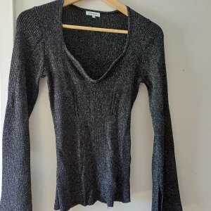 Glittrig svart ribbad tröja Bubbleroom - Snygg svart stickad tröja från Bubbleroom med glittriga inslag. Tröjan har lång ärm, v-ringad hals och sitter figurnära. Perfekt för dig som vill ha lite extra bling i vardagen. Materialet är stretchigt. Använd en gång på nyårsafton. 