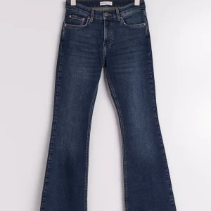 Bootcut jeans low  - Snygga mörkblå  jeans med klassisk bootcut passform. Jeansen har fem fickor, knapp och dragkedja framtill samt coola slitningar för en avslappnad vibe. Perfekta för dig som gillar retrostil och vill ha ett par jeans med lite extra attityd.