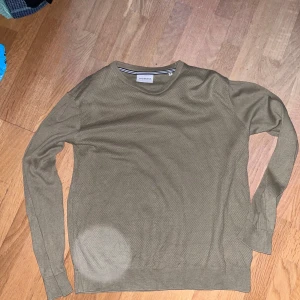 Beige stickad tröja från Lindbergh - Snygg beige stickad tröja från Lindbergh i storlek M. Tröjan har rund halsringning och diskret struktur i materialet. Perfekt för dig som gillar enkel och stilren design. Långa ärmar och ribbade muddar ger en clean look.