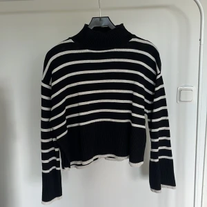 Randig stickad tröja från Gina Tricot - Svart och vit randig stickad tröja från Gina Tricot i storlek XS. Tröjan har hög krage, lång ärm och ribbade detaljer vid hals, ärmslut och nederkant. Denna tröja har som en liten slits i hörnen! Inget större tecken på användning förutom ärmkanterna.💞 PRIS GÅR ATT DISKUTERA!! Orginal pris; 299kr OBS! Liten i storlek
