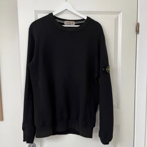 Stoneisland sweatshirt - Svart sweatshirt från Stone Island med klassisk rund hals och ribbade muddar. Tröjan har den ikoniska loggan på vänster ärm och är tillverkad i mjuk bomull. Perfekt för dig som gillar stilrena och snygga plagg med streetkänsla. Använd men omhändertagen. Nypris 1499. 
