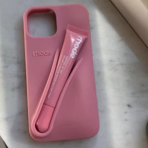 Rhode skal (iPhone 14/15) + Peptide Lip Tint Ribbon  - Rhode iPhone skal + Peptide Lip Tint i färgen ribbon, Innehåller peptider för extra vård. Läppglanset är oanvänd men skaletär  köpt för ett tag sedan från den egna hemsidan, men finns inte längre kvar i denna färg! Säljer då jag ska byta mobil.💗 (Ny kostar skal + läppglans 600kr!!)