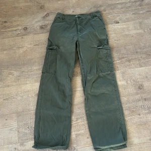 Gröna cargopants från Samsa Collection - Snygga gröna cargopants från Samsa Collection i storlek 36. Byxorna har raka ben, stora sidofickor och klassisk dragkedja framtill. Tillverkade i bomull för en skön och avslappnad känsla. Perfekta för en chill och streetig look.