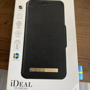 Svart plånbok från iDeal of Sweden - Stilren svart plånbok från iDeal of Sweden med guldfärgad logotyp framtill. Slimmad design med plats för två kort och struktur i materialet som ger en lyxig känsla. Perfekt för dig som vill ha både funktion och snygg stil.