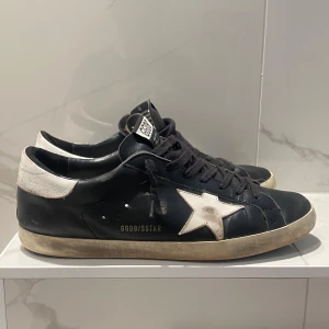 Golden Goose SuperStar skor - Säljer mina svarta Golden Goose skor| Modell: SuperStar | Storlek: 44| Skick: 7/10, inga defekter bara använda i 6 månader! Nypris: 5000kr, vårat 2099kr| Hojta gärna till ifall ni undrar över något 💭