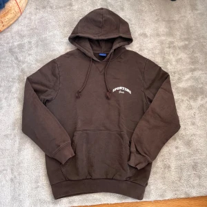Brun hoodie med tryck - Säljer en stilren brun hoodie med ett tryck i vitt på fram och baksida. Perfekt för en avslappnad stil. Priset kan diskuteras vid snabb affär😁