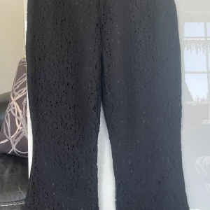Svarta spetsbyxor från Chacha - Snygga svarta byxor i spets från Chacha. Byxorna har en elegant design med ett vackert spetsmönster och är tillverkade i en blandning av bomull och nylon. Perfekta för att ge en stilfull touch till din outfit. Fodrade så ej genomskinliga. Hög midja 72-74 cm 