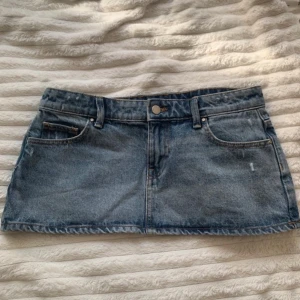 Jeanskjol från ONLY - Snygg jeanskjol från ONLY i klassisk blå denim. Kjolen har en kort längd och är försedd med knapp och dragkedja framtill. 